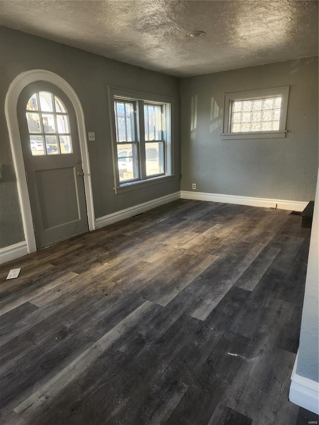 entrance foyer featuring a textured ceiling, a healthy amount of sunlight, and dark hardwood / wood-style floors