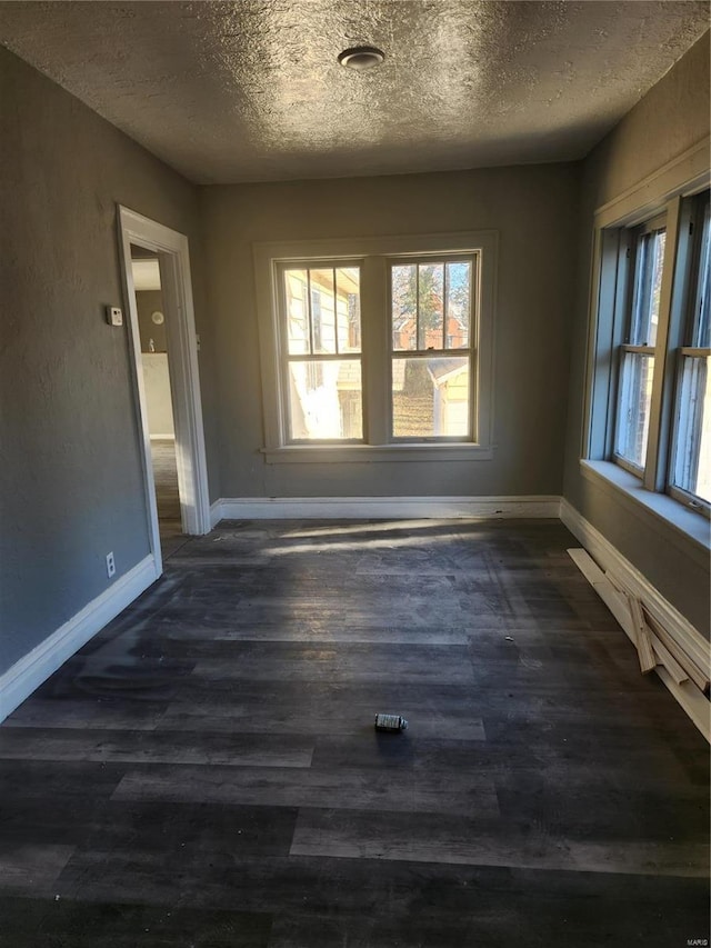 unfurnished room with dark hardwood / wood-style flooring, a healthy amount of sunlight, and a textured ceiling