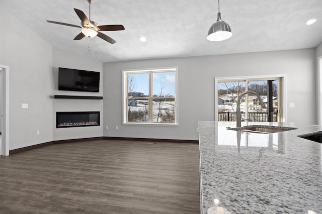 unfurnished living room with ceiling fan, dark hardwood / wood-style flooring, lofted ceiling, and sink