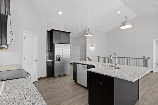 kitchen featuring appliances with stainless steel finishes, vaulted ceiling, sink, decorative light fixtures, and an island with sink