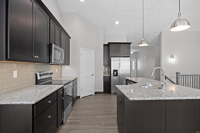 kitchen with pendant lighting, a kitchen island with sink, sink, and stainless steel appliances