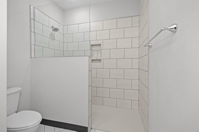 bathroom with tiled shower, tile patterned floors, and toilet