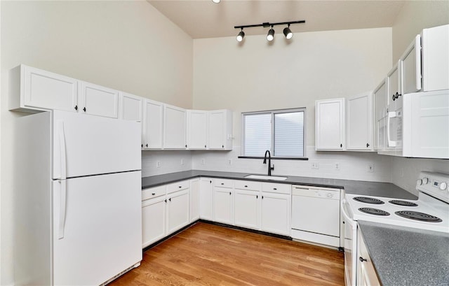 kitchen featuring white appliances, a towering ceiling, white cabinetry, decorative backsplash, and sink