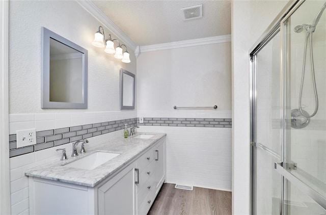 bathroom featuring vanity, tile walls, wood-type flooring, crown molding, and a textured ceiling