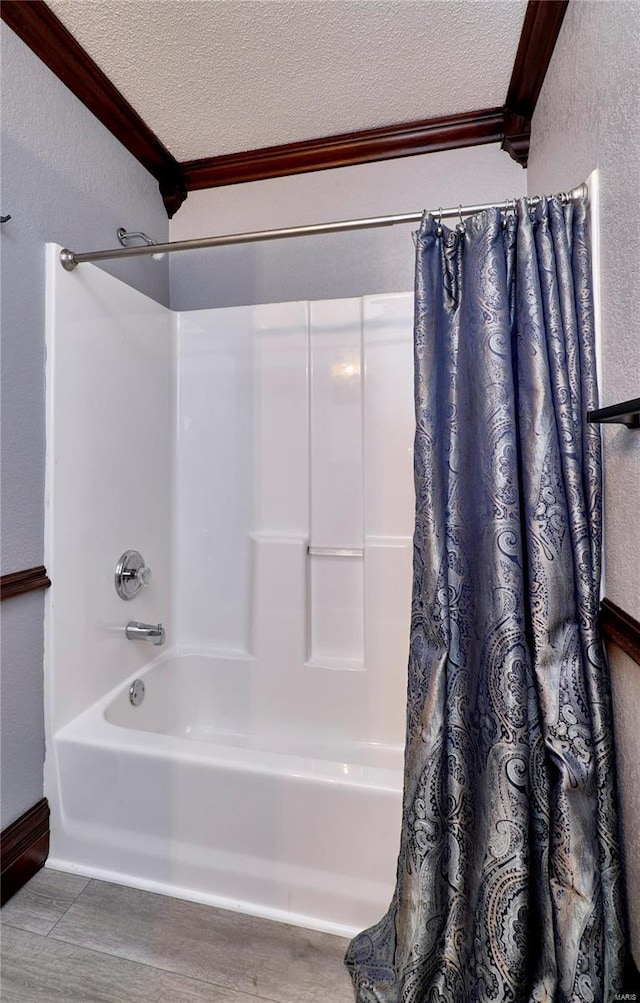 bathroom featuring a textured ceiling, ornamental molding, shower / tub combo, and hardwood / wood-style floors