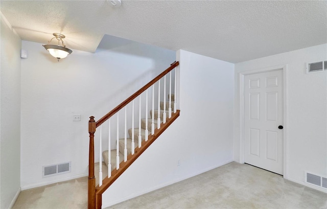 stairs with a textured ceiling and carpet flooring