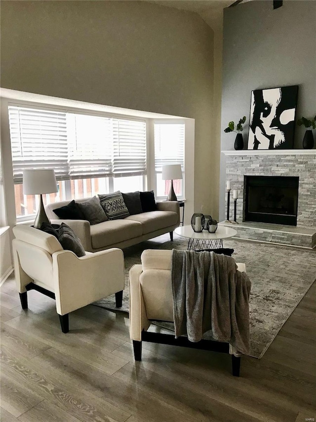 living area featuring a fireplace, wood finished floors, and a healthy amount of sunlight