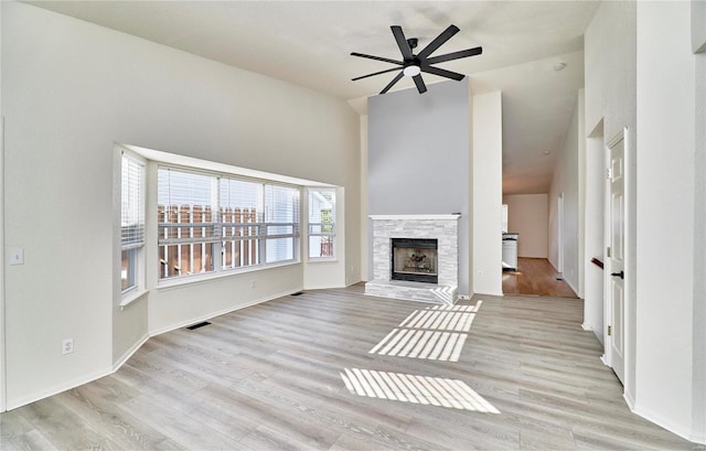 unfurnished living room with light wood-type flooring, ceiling fan, a fireplace, and visible vents