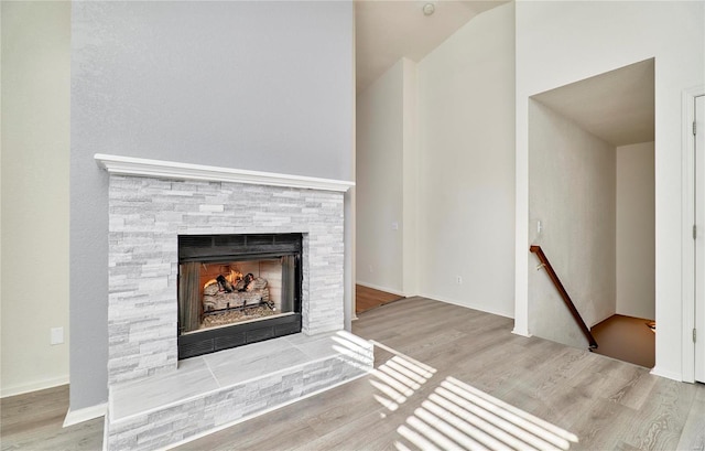 unfurnished living room featuring lofted ceiling, a fireplace, and wood finished floors