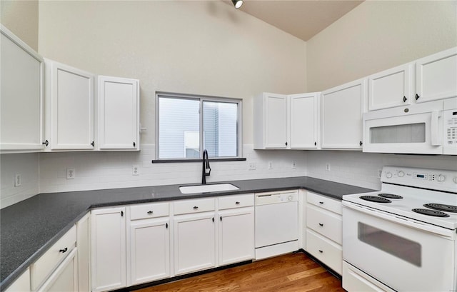 kitchen with white appliances, dark countertops, a sink, white cabinetry, and backsplash