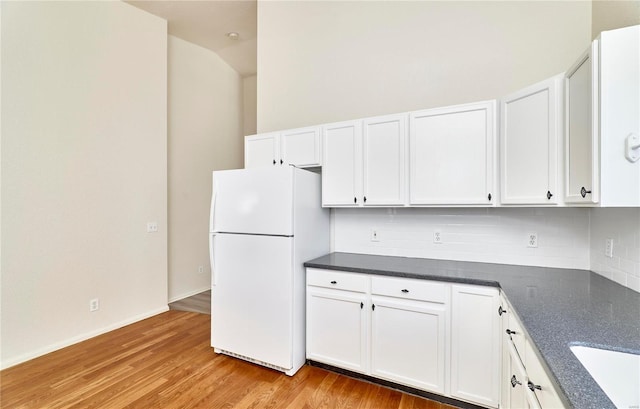 kitchen with tasteful backsplash, freestanding refrigerator, and white cabinets