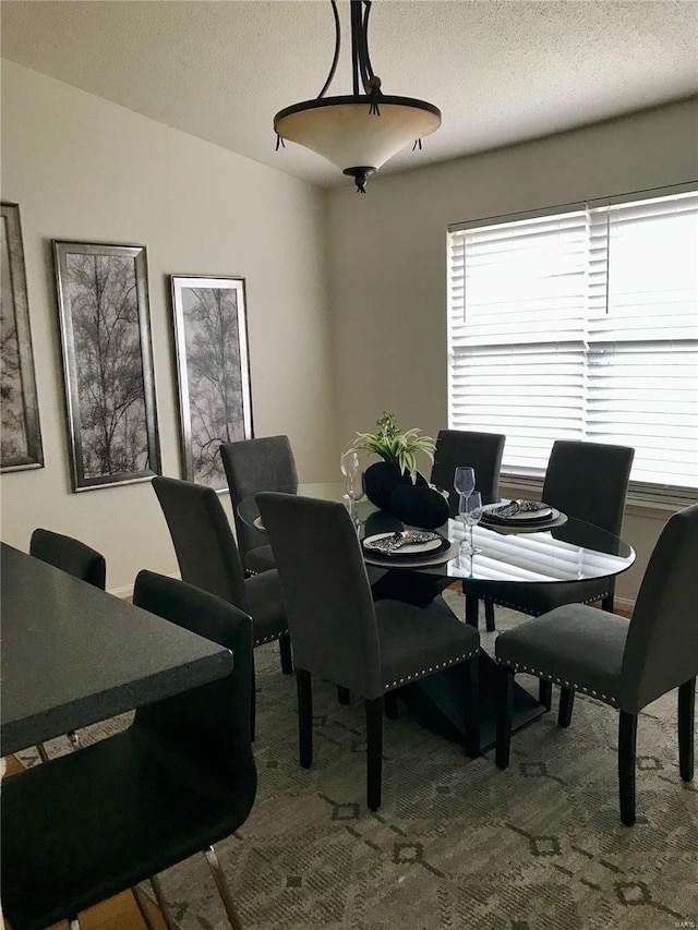 dining space with a textured ceiling, dark colored carpet, and lofted ceiling