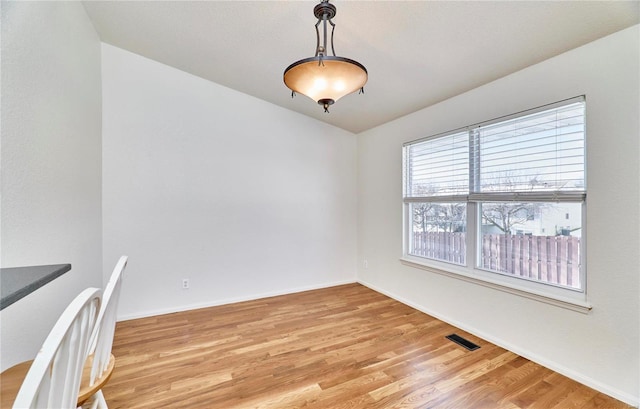 unfurnished dining area featuring light wood-type flooring, visible vents, and baseboards