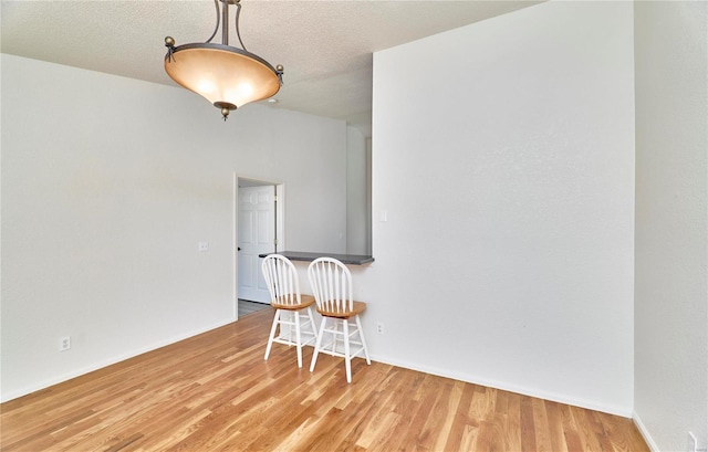 spare room featuring baseboards, a textured ceiling, and light wood-style floors