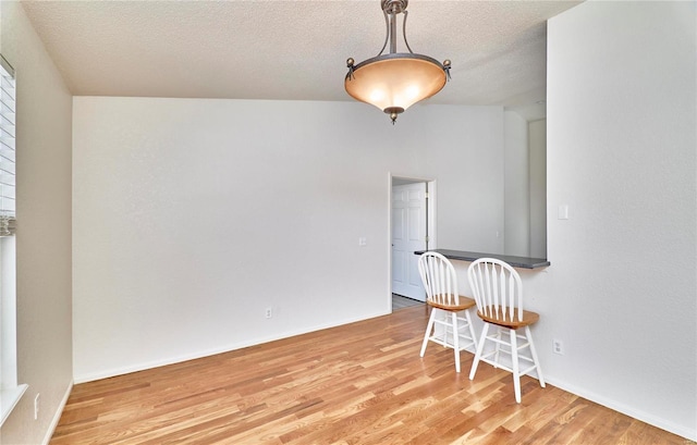 dining space featuring a textured ceiling, baseboards, and wood finished floors