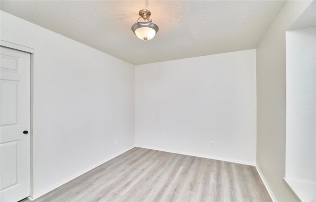 unfurnished room with light wood-style flooring, baseboards, and a textured ceiling