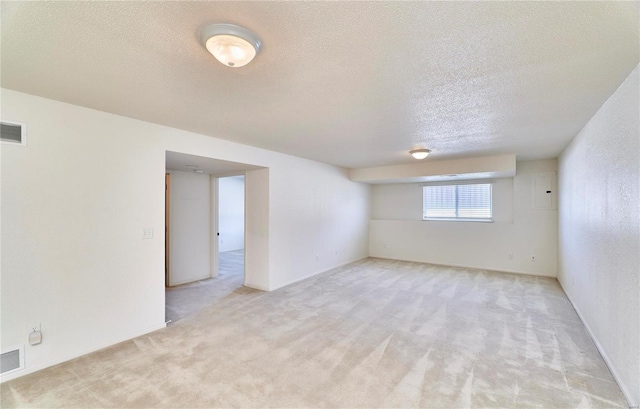 empty room with light carpet, a textured ceiling, and visible vents