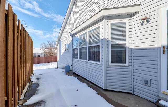 view of snow covered exterior with fence