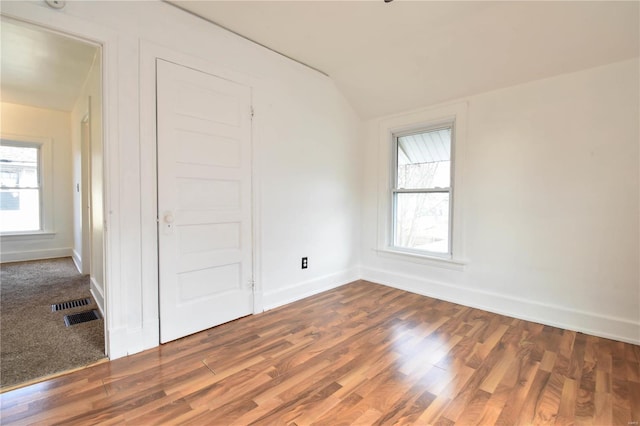 unfurnished bedroom featuring hardwood / wood-style floors, vaulted ceiling, and multiple windows