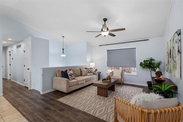 living room featuring dark wood-type flooring, ceiling fan, and vaulted ceiling