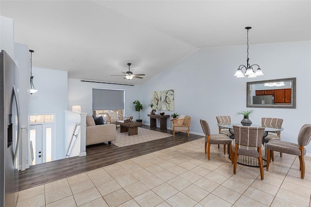 tiled dining room with ceiling fan with notable chandelier and vaulted ceiling