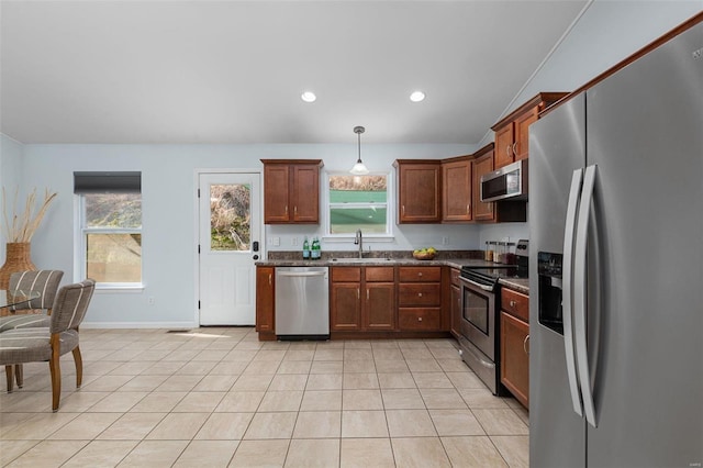 kitchen with light tile patterned flooring, appliances with stainless steel finishes, decorative light fixtures, sink, and a healthy amount of sunlight