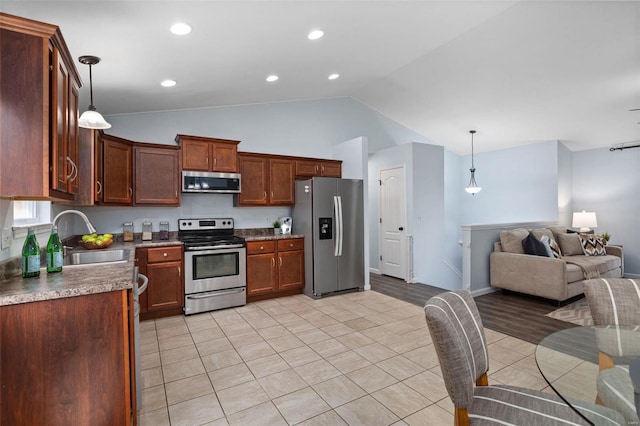 kitchen featuring pendant lighting, sink, light tile patterned floors, stainless steel appliances, and vaulted ceiling