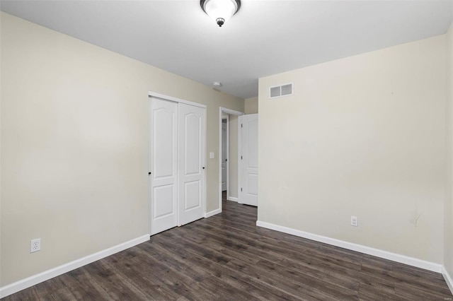 unfurnished bedroom featuring dark hardwood / wood-style flooring and a closet