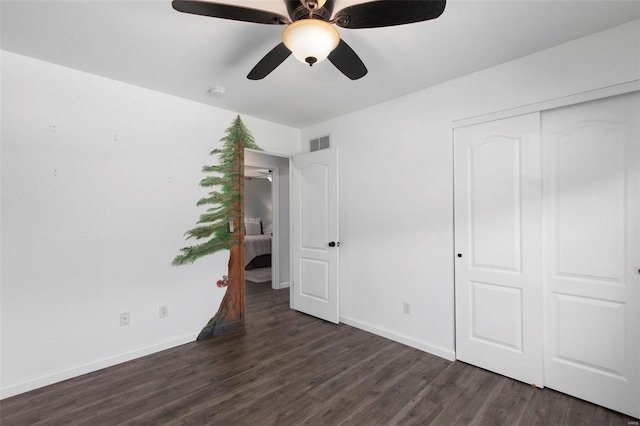 unfurnished bedroom with dark wood-type flooring, a closet, and ceiling fan