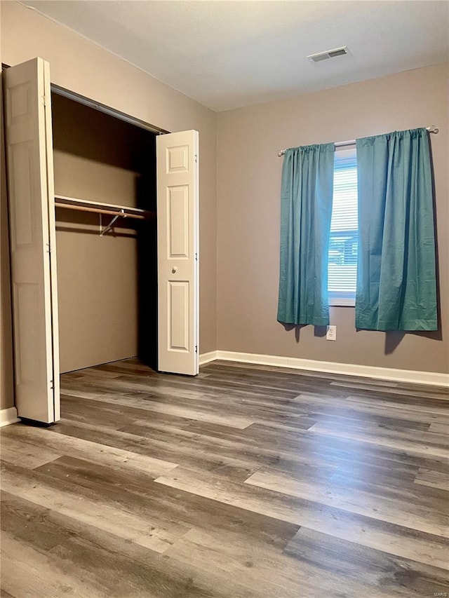 unfurnished bedroom featuring hardwood / wood-style floors and a closet