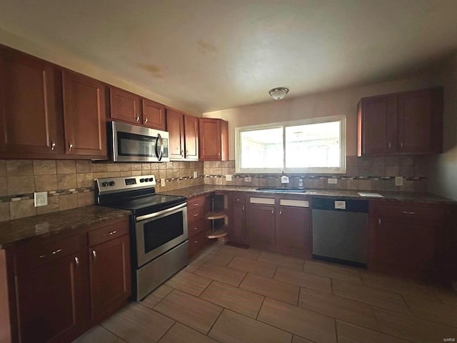 kitchen with light tile patterned flooring, appliances with stainless steel finishes, decorative backsplash, and sink