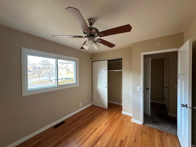 unfurnished bedroom featuring ceiling fan, light hardwood / wood-style floors, and a closet