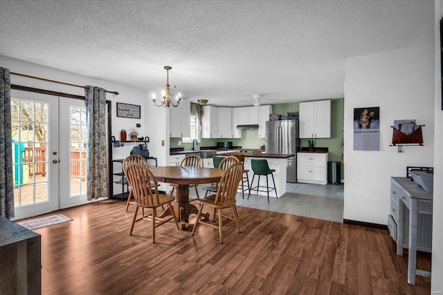 dining room with french doors, a textured ceiling, dark wood-type flooring, and a notable chandelier