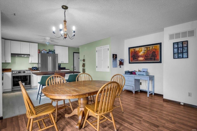 dining space with ceiling fan with notable chandelier, a textured ceiling, and dark wood-type flooring