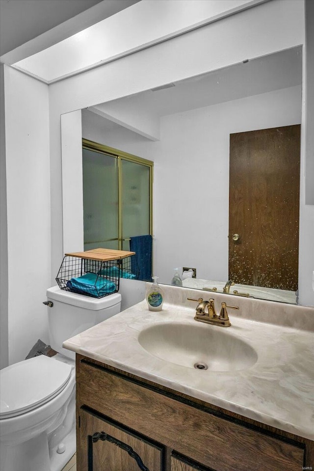 bathroom featuring vanity, toilet, and a shower with door