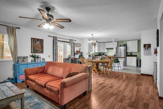 living room featuring ceiling fan with notable chandelier, a textured ceiling, and hardwood / wood-style flooring