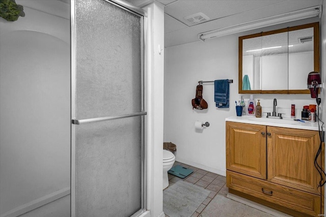 bathroom featuring tile patterned floors, vanity, toilet, and a shower with door