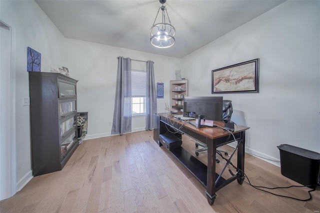 home office with an inviting chandelier and light hardwood / wood-style flooring