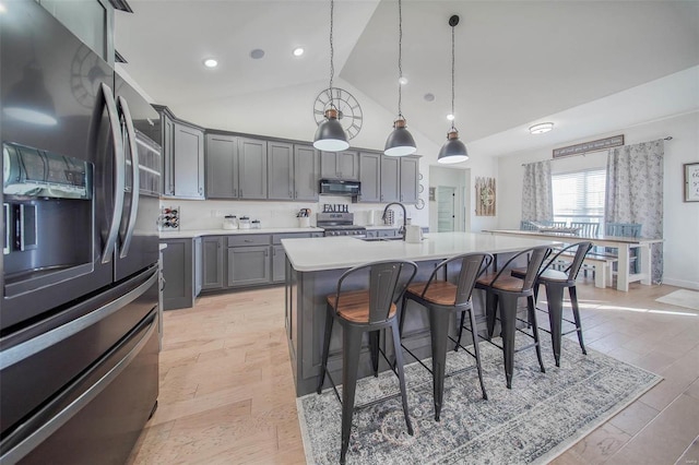 kitchen with sink, gray cabinetry, appliances with stainless steel finishes, pendant lighting, and a kitchen island with sink