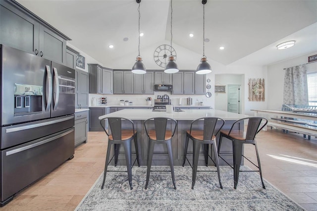 kitchen featuring a spacious island, stainless steel appliances, decorative light fixtures, and a kitchen bar