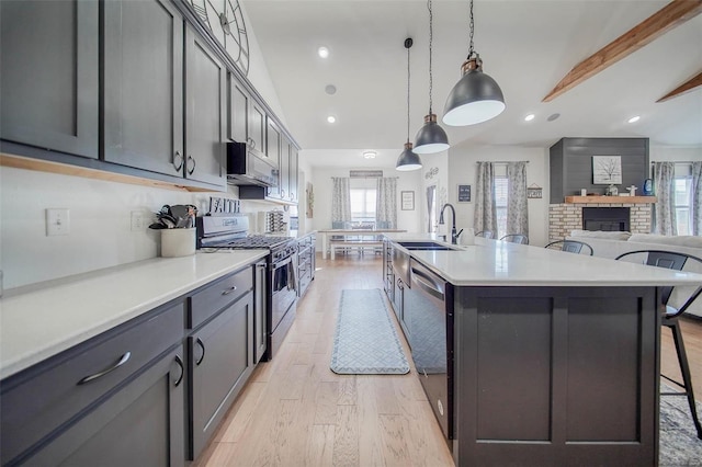 kitchen featuring a breakfast bar, sink, appliances with stainless steel finishes, pendant lighting, and a large island