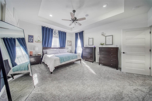 bedroom featuring a raised ceiling, carpet floors, and ceiling fan