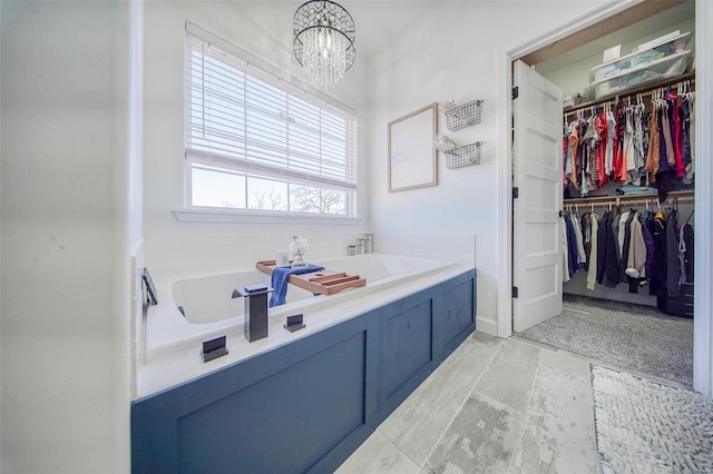 bathroom featuring tile patterned flooring, a notable chandelier, and a tub to relax in