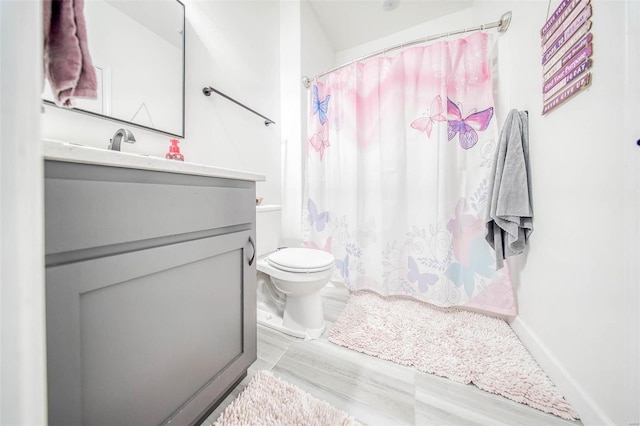 bathroom featuring vanity, curtained shower, and toilet