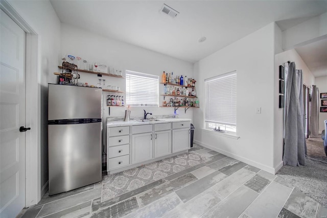 kitchen with white cabinetry, stainless steel fridge, and sink