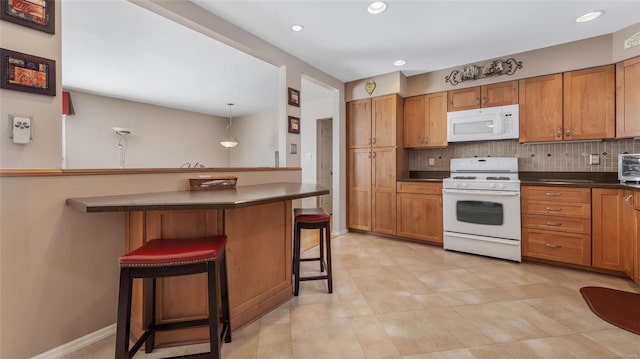 kitchen with pendant lighting, white appliances, a kitchen breakfast bar, tasteful backsplash, and kitchen peninsula