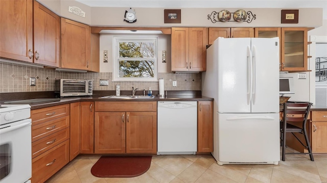 kitchen featuring backsplash, sink, light tile patterned flooring, and white appliances