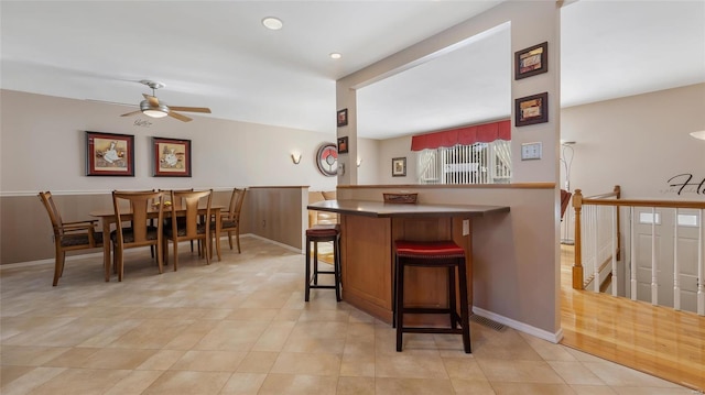 kitchen featuring a kitchen breakfast bar, ceiling fan, kitchen peninsula, and light tile patterned floors