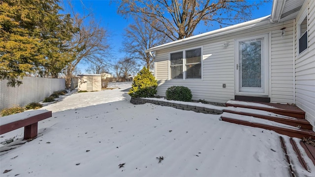 snowy yard featuring a patio area and a storage shed