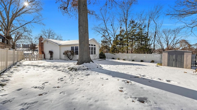 snow covered back of property with a storage unit